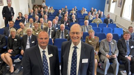 Two men standing in front of a seated audience of people