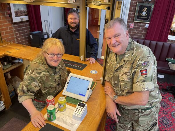 Three people by a small computer screen and payment console