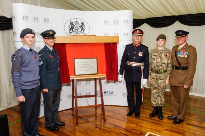 five individuals in a line with a plaque in the middle of them,