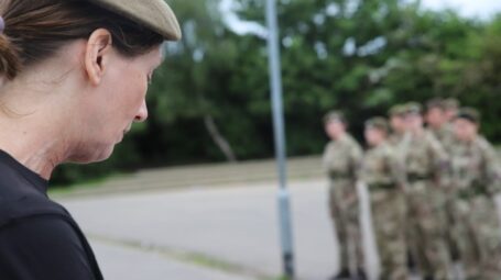 a woman looks down at the ground with a group of people blurred in the background