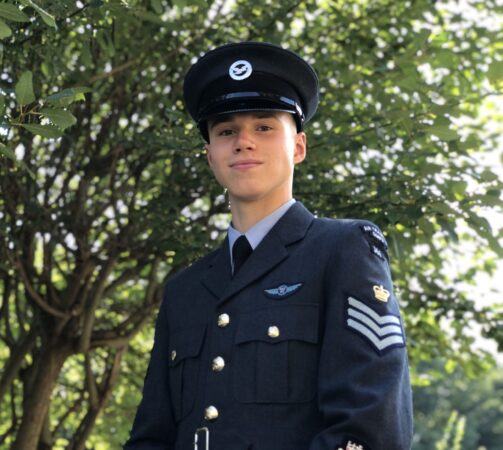 Young man in uniform looking down at the camera and smiling