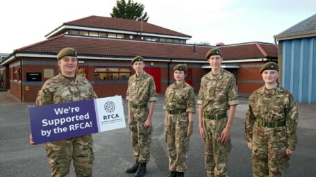 Adult instructor in front of Wolfe Armoury with cadets in background