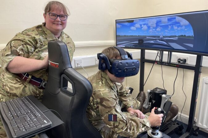 Volunteer with virtual reality head monitor at computer screen, together with a colleague looking on