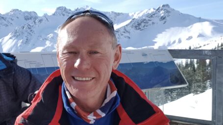 Man with ski goggles against mountain backdrop